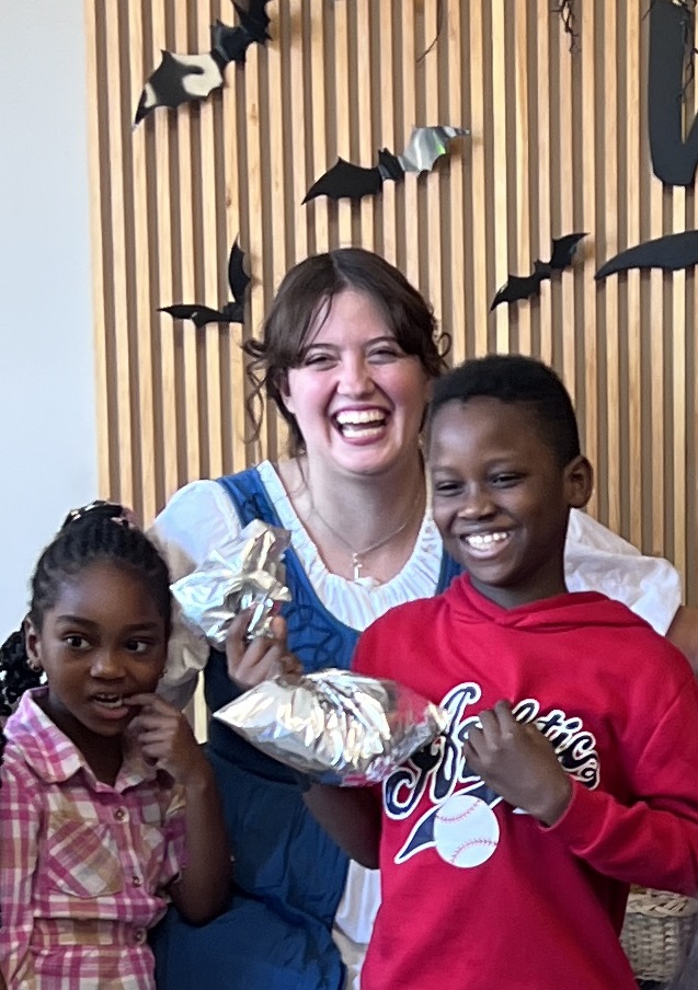 Photo of a smiling woman and two children in front of a background of paper bats