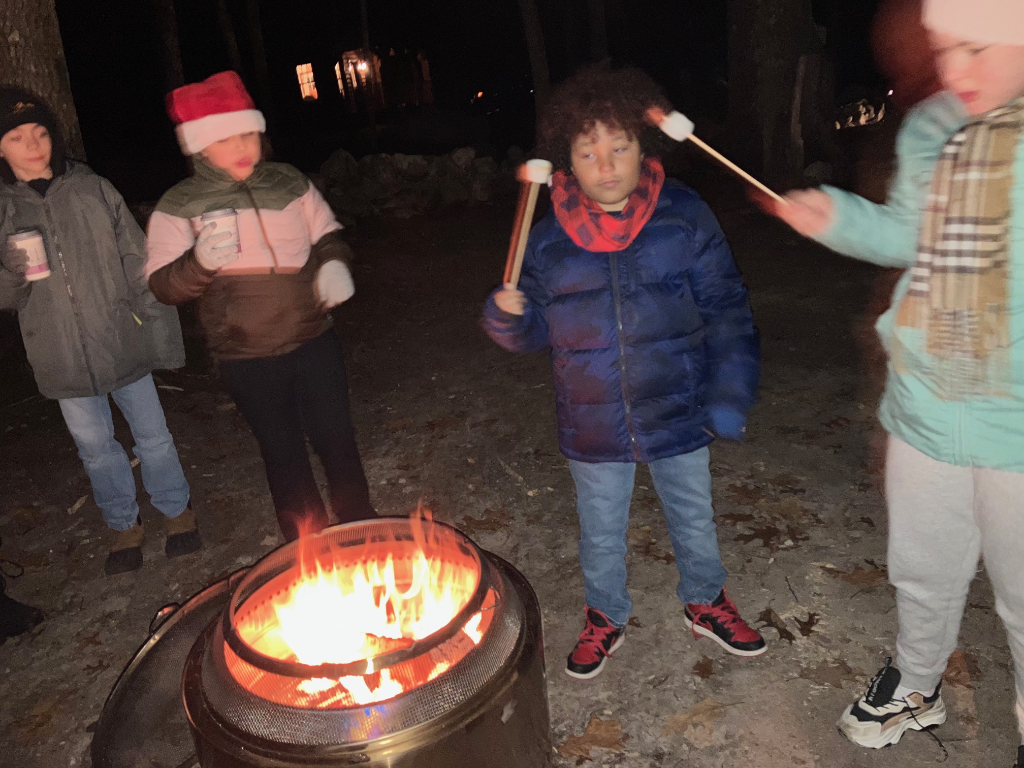 Photo of two boys bobbing for apples outside while a third boy waits for his turn